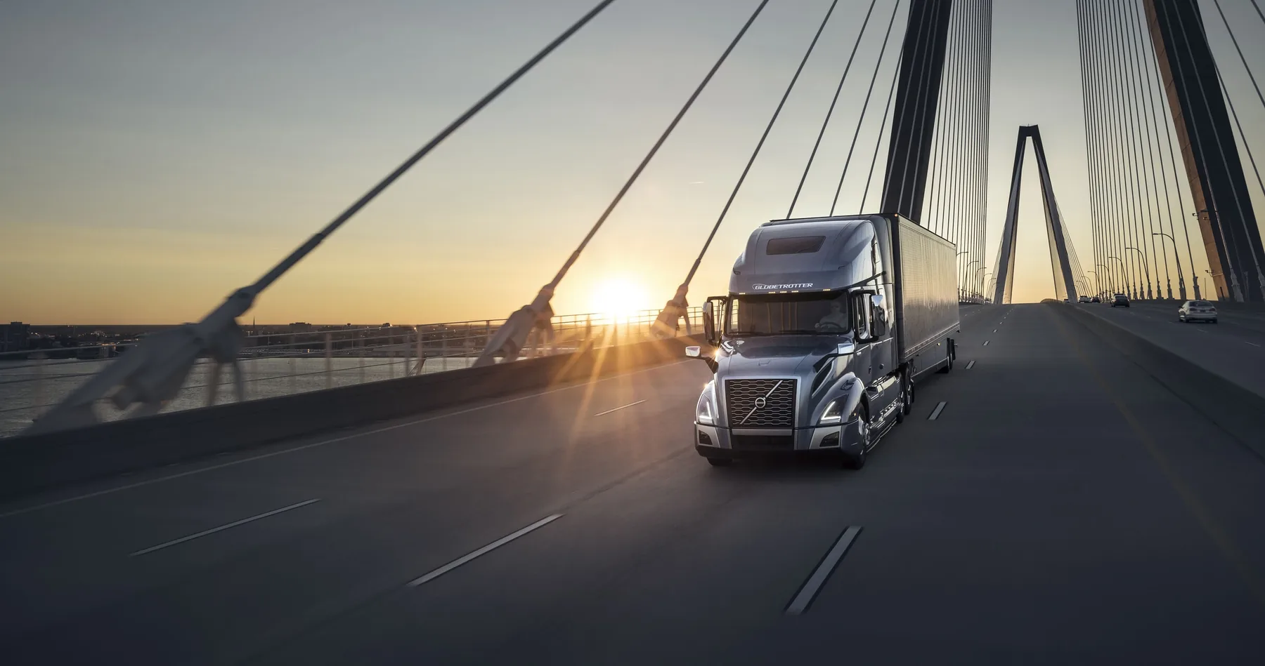 Volvo tractor-trailer crossing a bridge at sunset